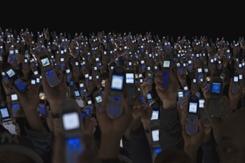 Crowd holding up smartphones.